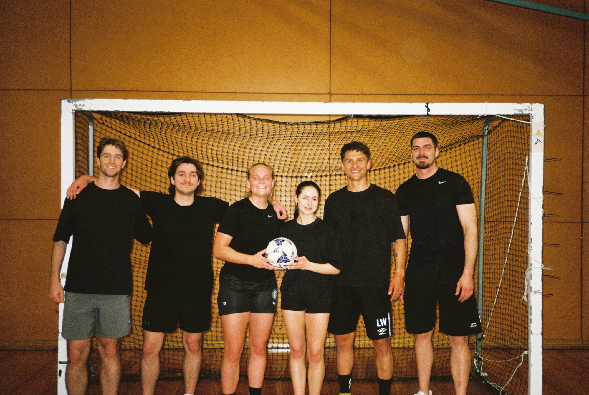Six FIS players standing together in front of an indoor futsal goal